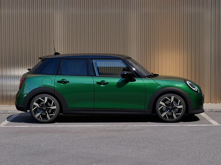 Side view of the MINI Cooper 5-Door in British Racing Green and Roof in Black parking.